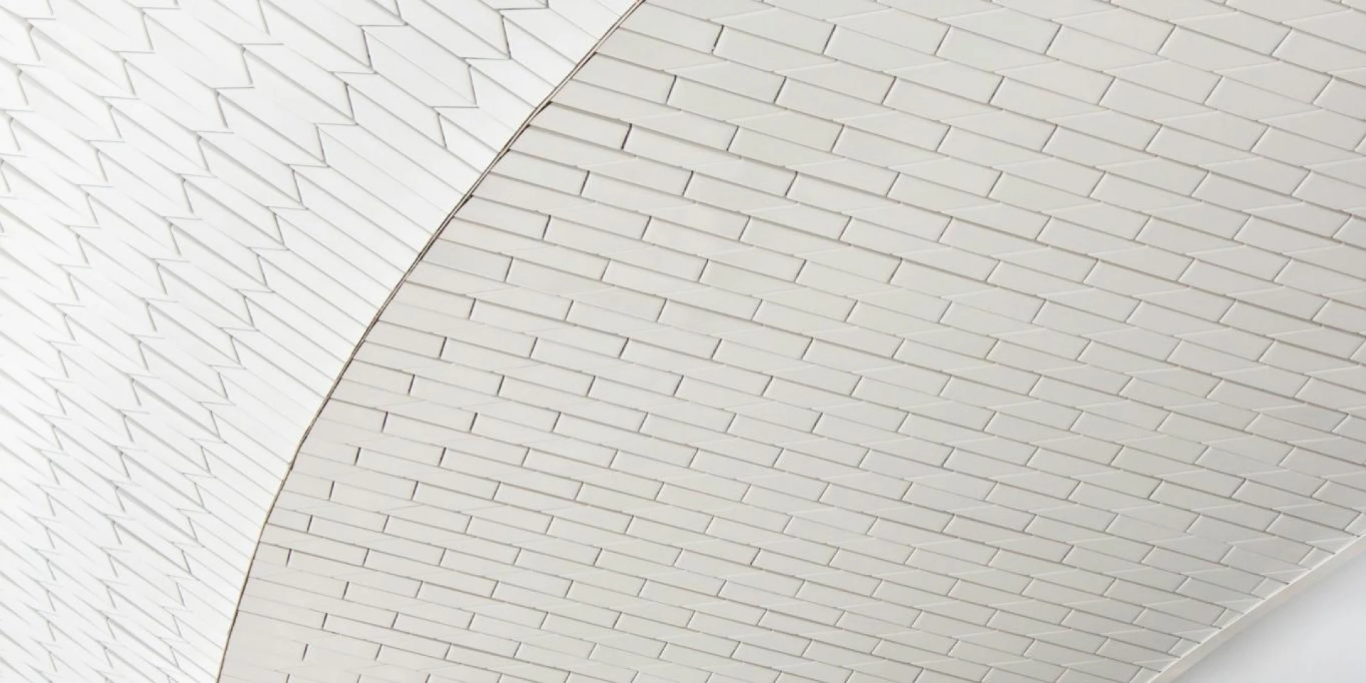 Interior of a modern structure with a white tiled ceiling curving gracefully, featuring geometric patterns.