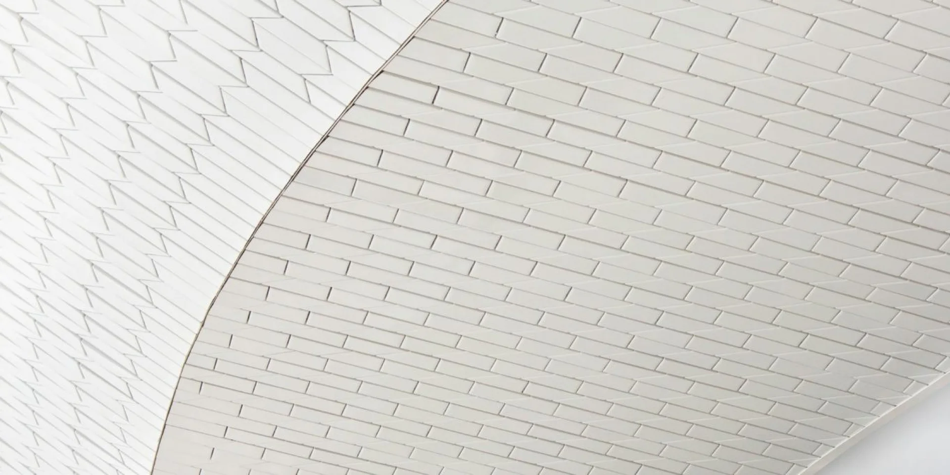 Interior of a modern structure with a white tiled ceiling curving gracefully, featuring geometric patterns.
